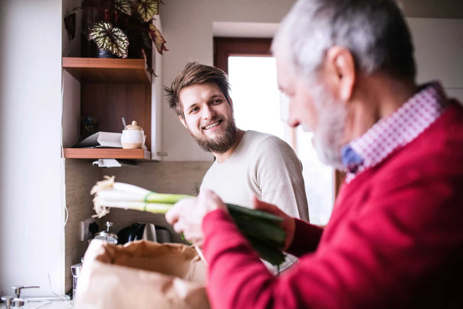 A Here 2 Helper unpacking groceries in the kitchen alongside a customer
